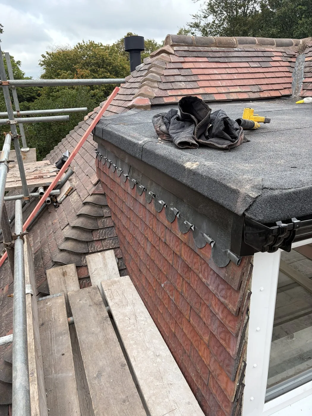 New mineral-surfaced flat roofing and black roof-edge trim during the Ormskirk job